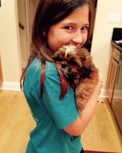 A girl holding a small dog in her arms.