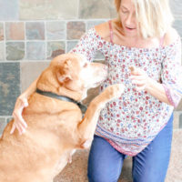 A woman and her dog playing with each other.