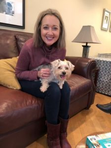 A woman sitting on the couch with her dog.