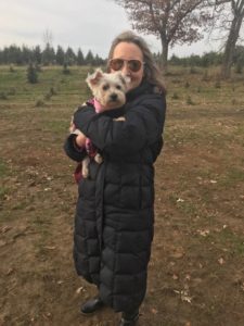 A woman holding her dog in the middle of an open field.