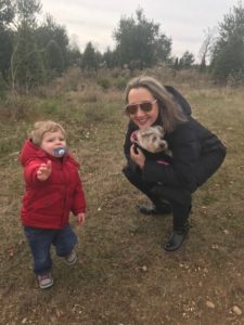 A woman and child in the woods with a dog.