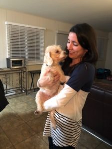 A woman holding her dog in the living room.