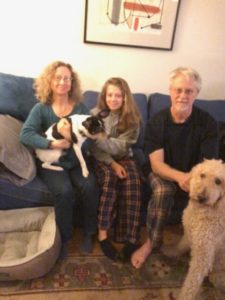 A family sitting on the couch with their dog